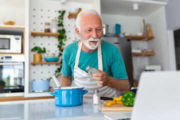 Happy senior man having fun cooking at home - Elderly person preparing health lunch in modern kitchen - Retired lifestyle time and food nutrition concept