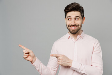 Young fun caucasian man 20s he wear basic white shirt point index finger aside indicate on workspace area copy space mock up isolated on plain grey background studio portrait People lifestyle concept