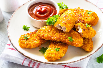 Chicken nuggets with ketchup sauce at white table.