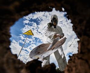 Close-up view of shovel with which scientist in gas mask digging hole to study composition of soil...