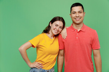 Obraz premium Young fun couple two friends family man woman wear basic t-shirts together girlfriend put head lean on boyfriend's shoulder looking camera isolated on pastel plain light green color background studio.