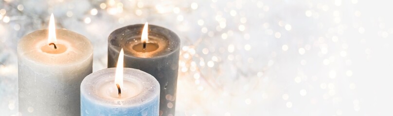 Christmas background - burning advent candles in the snow with golden bokeh lights - wintry xmas...