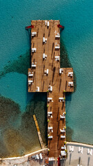 Aerial drone view to the beach with white sand, pier with sunchairs and sea. Luxury summer vacation and resort.