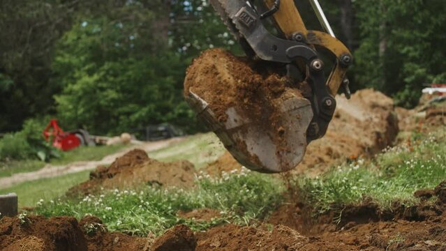 Excavator bucket picking up and dumping dirt (4k 30p Slow Motion)