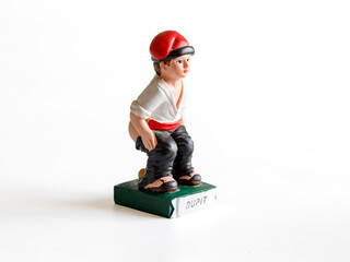 Caganer wearing traditional hat barretina, originally character in Catalan mythology, nativity figurine in detail of man doing poop, typical christmas statue from Catalonia isolated on white close up