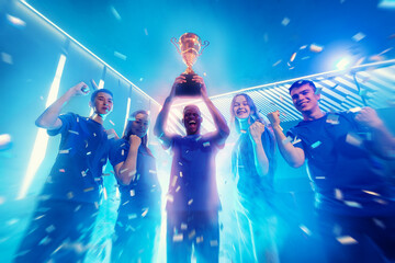 Happy Winner team gamer holding cup trophy prize of victors video games tournament. Concept cyber...