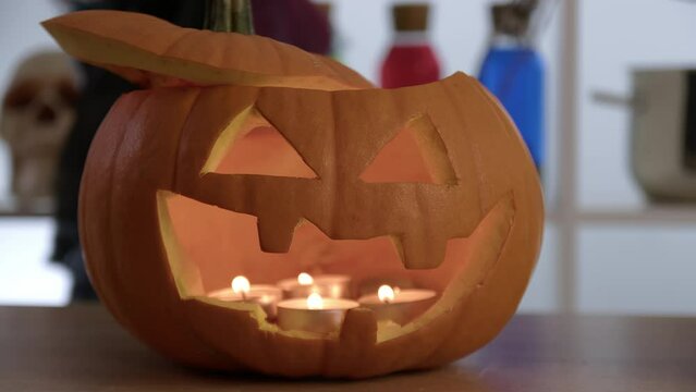 A close -up of the pumpkin shines on Halloween. Candles burn in an orange pumpkin. Horror Halloween concept. Halloween pumpkin smile and scary eyes for party night. 