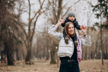 Mother with little son together in autumn park