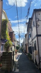 The narrow street of Tokyo, Nezu district year 2022 on a sunny day with clouds, street wires and varieties of retro houses