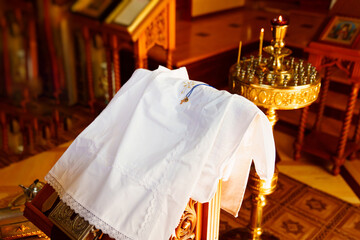 a white baptismal shirt and a cross on a table in the church during baptism.