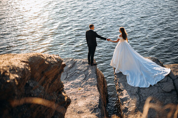 Smiling young newly married wedding couple on walk in rocky cliff