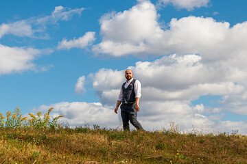 Naklejka na ściany i meble handsome guy in a suit among the field against the blue sky