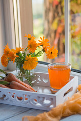 Carrot juice in a glass and fresh carrots on the table.
