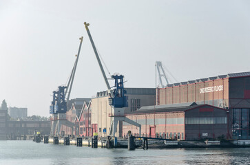 Fototapeta premium Rotterdam, The Netherlands, September 4, 2022: view from the Nieuwe Maas river towards Heyplaat, with industrial sheds now used for other purposes