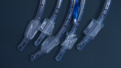 endotracheal tubes of different diameters lie on a dark background.  close-up
