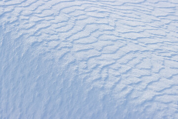 Beautiful winter background with snowy ground. Natural snow texture. Wind sculpted patterns on snow surface.