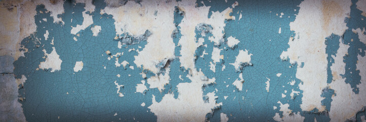 Peeling paint on the wall. Panorama of a concrete wall with old cracked flaking paint. Weathered rough painted surface with patterns of cracks and peeling. Grunge texture for wide panoramic background