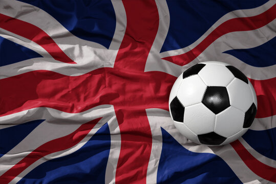 vintage football ball on the waveing national flag of great britain background. 3D illustration