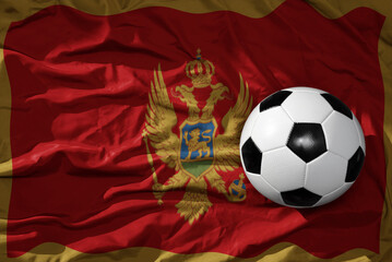 Fototapeta premium vintage football ball on the waveing national flag of montenegro background. 3D illustration