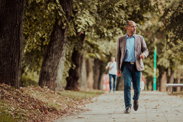 Fototapeta premium Focused businessman in a suit walking in the park