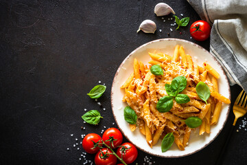 Pasta with tomato sauce, basil and parmesan on dark table. Penne pasta with tomato sauce alla arrabbiata. Top view with copy space.