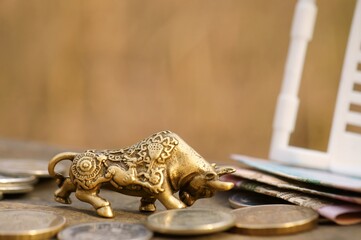 A figure of a metal bull and coins in close-up.