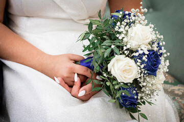 Obraz na płótnie Canvas the bride's hands hold a bouquet with blue flowers