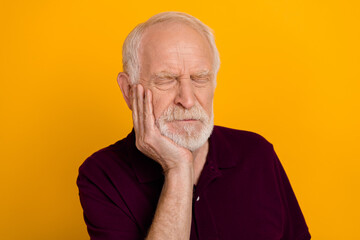Photo of sad old white hairdo man hold cheek wear blueberry t-shirt isolated on yellow color background