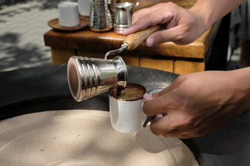 Barista pours freshly made Turkish coffee into a cup, close-up. A professional barista prepares...