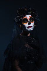 woman in creepy halloween makeup and black costume of witch on dark background.
