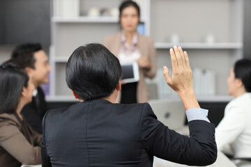 Rear view volunteer man or  businessman raising hand during training seminar presentation at...