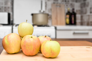 Apples on a cutting board on a table against a blurred home kitchen interior