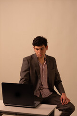 Executive with laptop at a table in a brown suit. curly haired venezuelan
