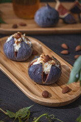 Fresh ripe raw figs with mascarpone cheese, almonds and honey or maple syrup in wooden tray.