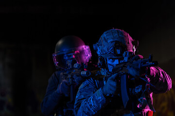 Naklejka premium Modern warfare soldiers in dark with combat ammunition and weapons in the hands of equipped laser sights are in battle order. Mixed media. 