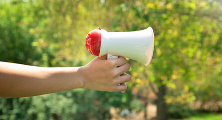 Caucasian woman holding megaphone at outdoor.
