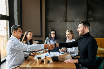 Successful cooperation. Two men shake hands in a meeting in the office