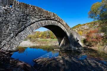 Fototapeta na wymiar View of the traditional stone Mylos Bridge in Epirus, Greece in Autumn.