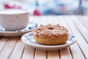 Natural no sugar doughnut and cappuccino in white ceramic cup on wooden table. Aesthetic coffee time. Top view food