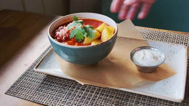 Serving Hungarian goulash soup with sour cream in restaurant close-up.