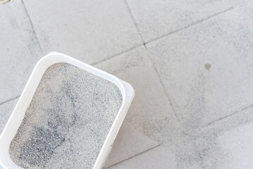 Fototapeta na wymiar A full bucket of polymeric paver sand on top of gray concrete patio stone paver walkway
