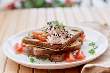 Seasonal vegan sandwiches with sourdough bread, tomatoes, herbs, quinoa and vegan sause. Healthy breakfast outside