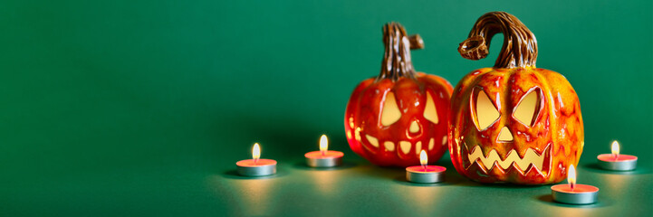 Halloween composition with diy ceramic pumpkins jack lantern and candles on pine green background