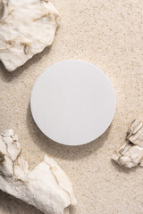 Natural cosmetic background for product presentation. Rocks and white podium on the sand. Top view.