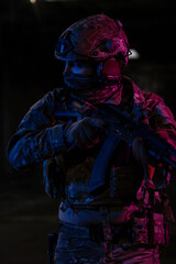 Army soldier in Combat Uniforms with an assault rifle and combat helmet night mission dark...