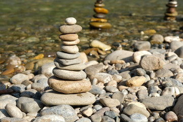 Fototapeta na wymiar Stones arranged in zen towers by the river bed on a summers day