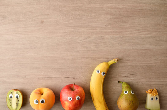 Raw of funny fruit with eyes on wooden bench top