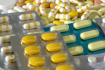 Pile of medical pills in white, yellow and other colors. Pills in plastic packaging. Healthcare and medicine concept.