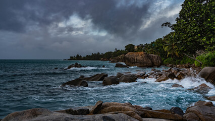 Evening on a tropical island. The waves of the turquoise ocean beat against the coastal boulders...