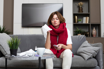 Suffering from flu woman sitting on the couch and treating herself